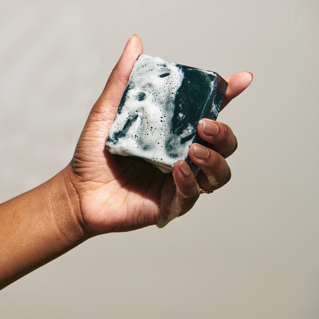 woman-holding-a-lathered-bar-of-charcoal-soap
