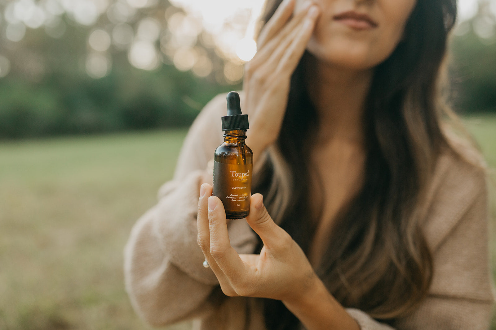 woman-applies-anti-aging-serum-with-a-field-as-the-background