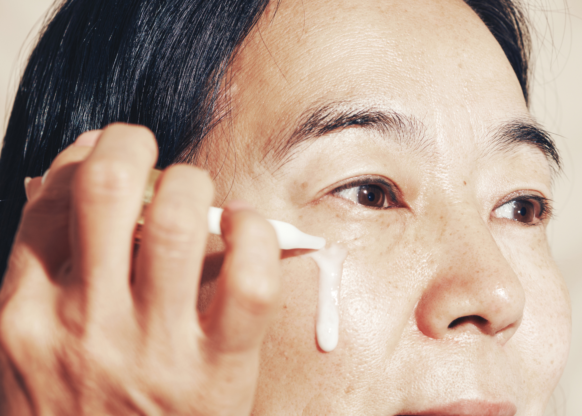 woman-applying-bakuchiol-serum-to-her-cheeks
