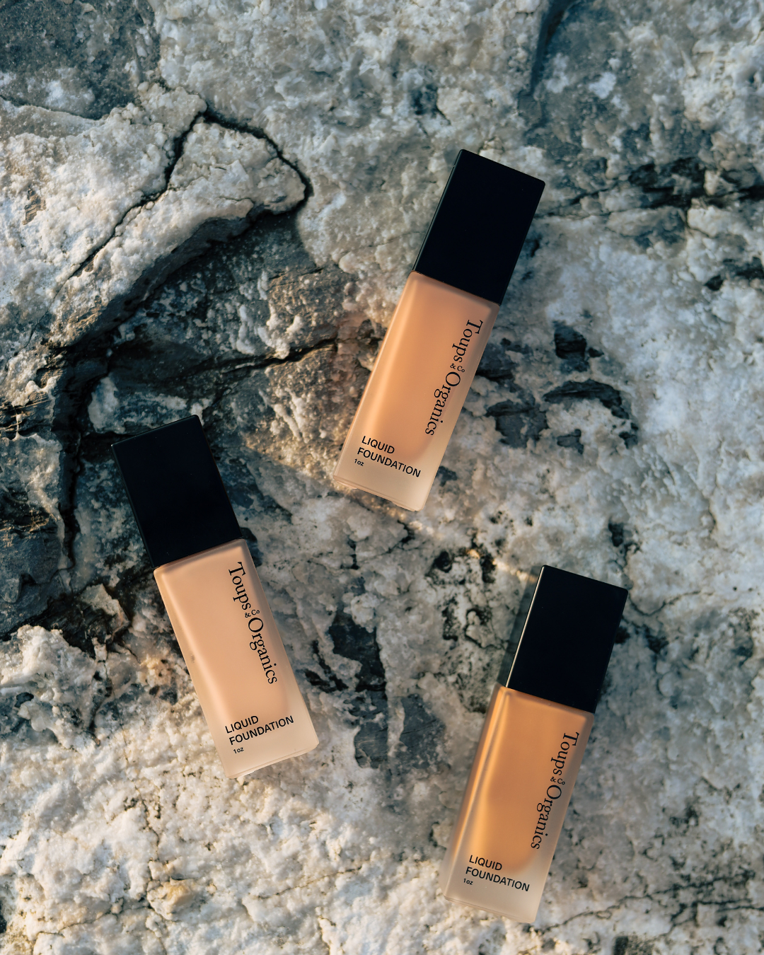 three-different-shades-of-foundation-bottles-with-a-rock-background