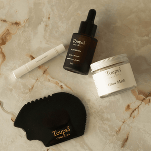 The Toups and Co Organics Skin Therapy Set is arranged on a marble surface, offering a complete skincare routine upgrade.