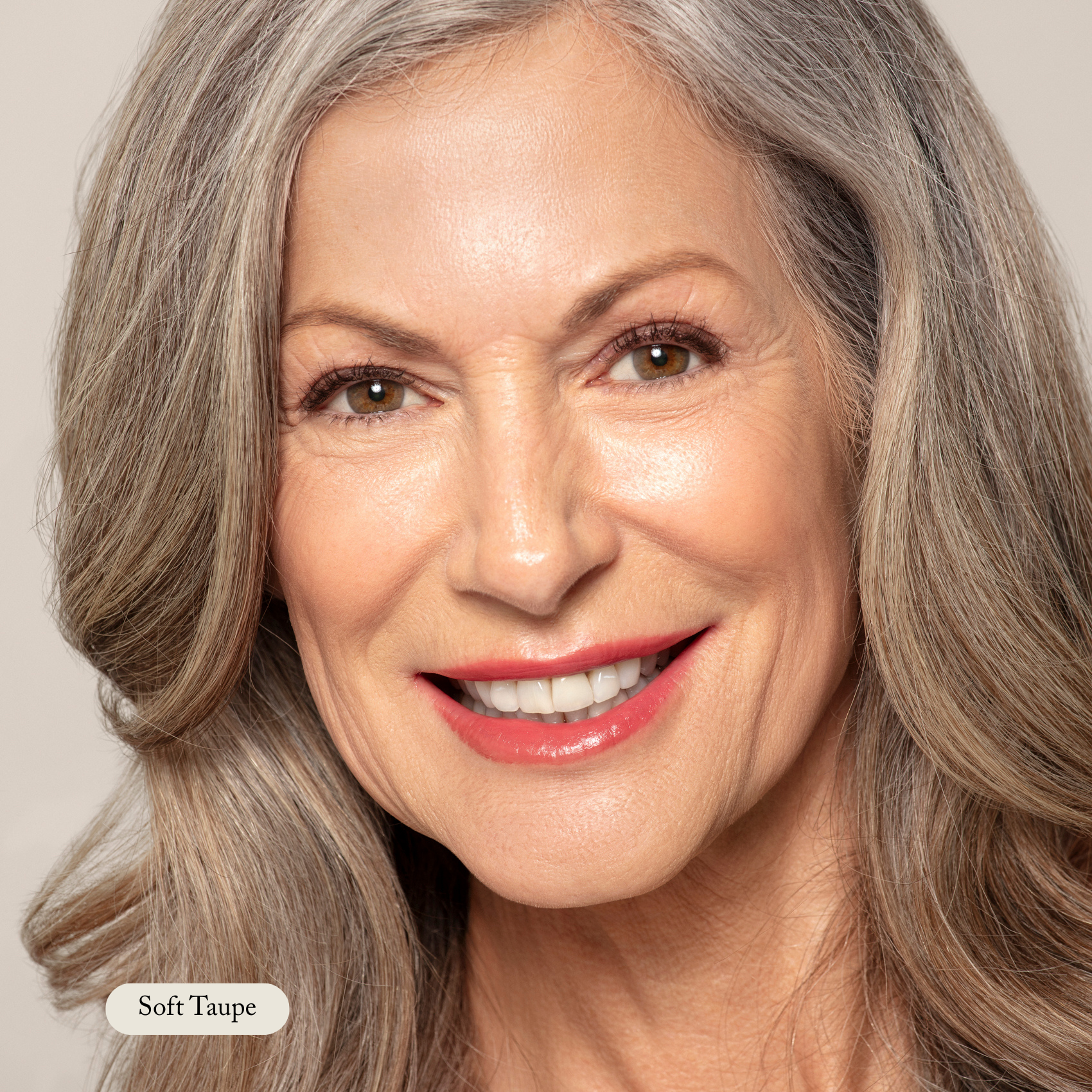 Close-up of an older woman with long gray hair, smiling, wearing natural makeup with soft taupe lipstick and perfectly defined brows using the Brow Pencil from Toups and Co Organics for a buttery smooth application.