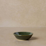 green-pottery-bowl-for-mixing-face-masks-displayed-on-brown-background