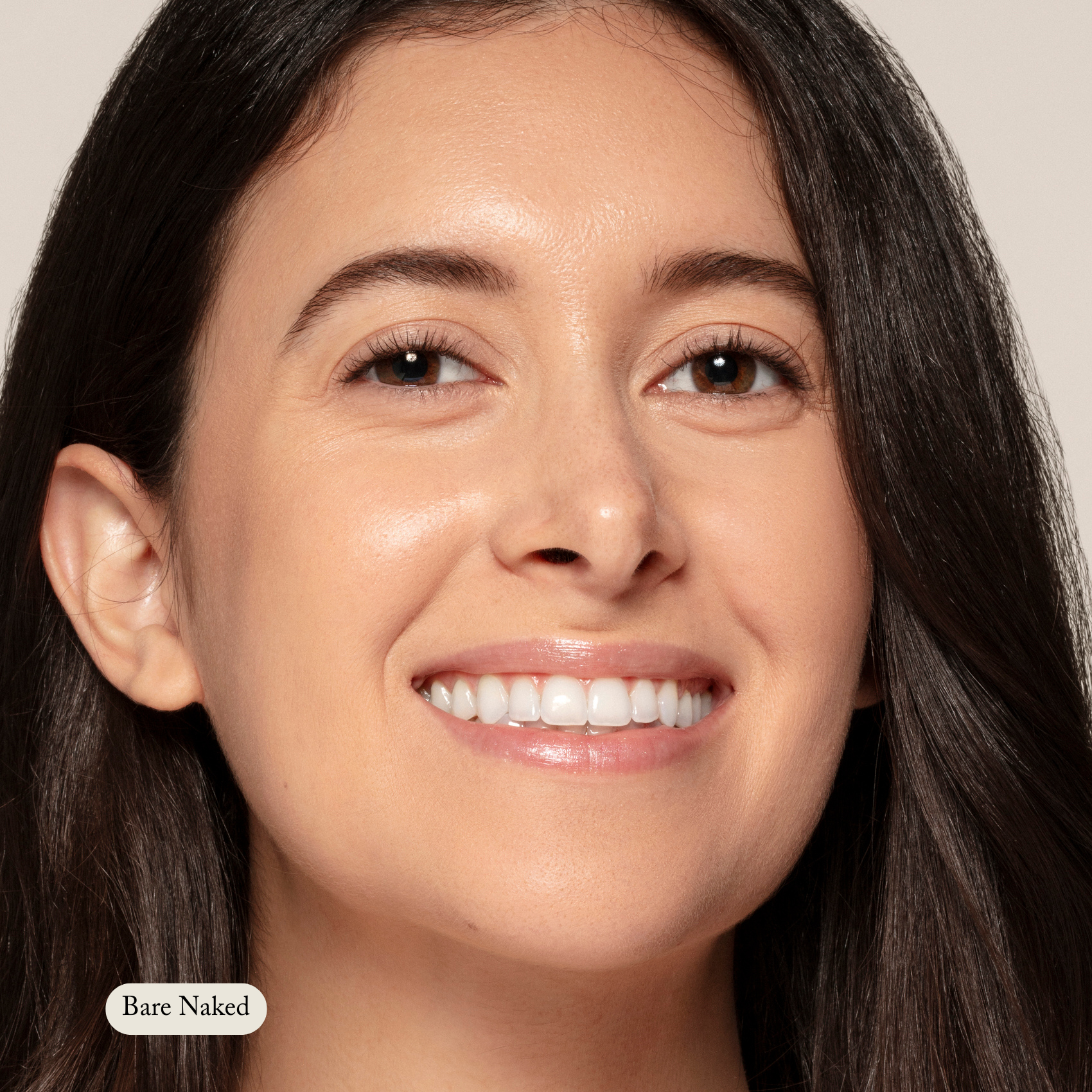 A woman with long dark hair and clear skin smiles at the camera, radiating natural hydration. The label Toups and Co Organics Concealer appears on the bottom left.