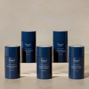 Five dark blue sticks of Toups and Co Organics extra strength natural deodorant in various scents, arranged on a tiered display.