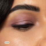 A close-up of a closed eye showcases highly pigmented lavender and purple Natural Eyeshadow Singles by Toups and Co Organics, along with a defined eyebrow and smooth skin.