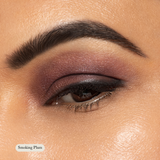 Close-up of an eye adorned with Toups and Co Organics Natural Eyeshadow Singles in a bold plum shade, paired with sharp eyeliner and a defined brow. Text on image: Smoking Plum.