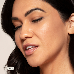 A woman with clear skin and dark hair gazes down, softly smiling and showcasing her sensitive eyes enhanced by Toups and Co Organics Natural Eyeliner.