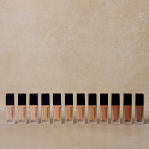 twelve-shades-of-nontoxic-liquid-foundation-lined-up-against-brown-background
