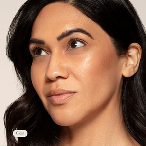 A woman with long dark hair and clear, glowing skin looks upward; Clear appears in a white label, highlighting her radiant look achieved using Toups and Co Organics Organic Lip Gloss made from safe, nontoxic ingredients.