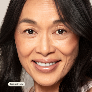 A middle-aged woman with long dark hair smiles at the camera; a tag reads Toups and Co Organics, highlighting her radiant look—thanks to Organic Lip Gloss made with safe, nontoxic ingredients.