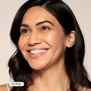 A woman with long dark hair and tan-beige skin smiles, her radiant complexion highlighted by the even lighting and neutral background—showcasing the benefits of Toups and Co Organics Mineral Makeup.
