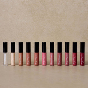 eleven-shades-of-organic-lip-gloss-displayed-against-brown-background