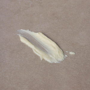 A small smear of Toups and Co Organics Tallow Balm - Vanilla + Almond, made from nourishing grass-fed tallow, on a sheet of parchment paper.