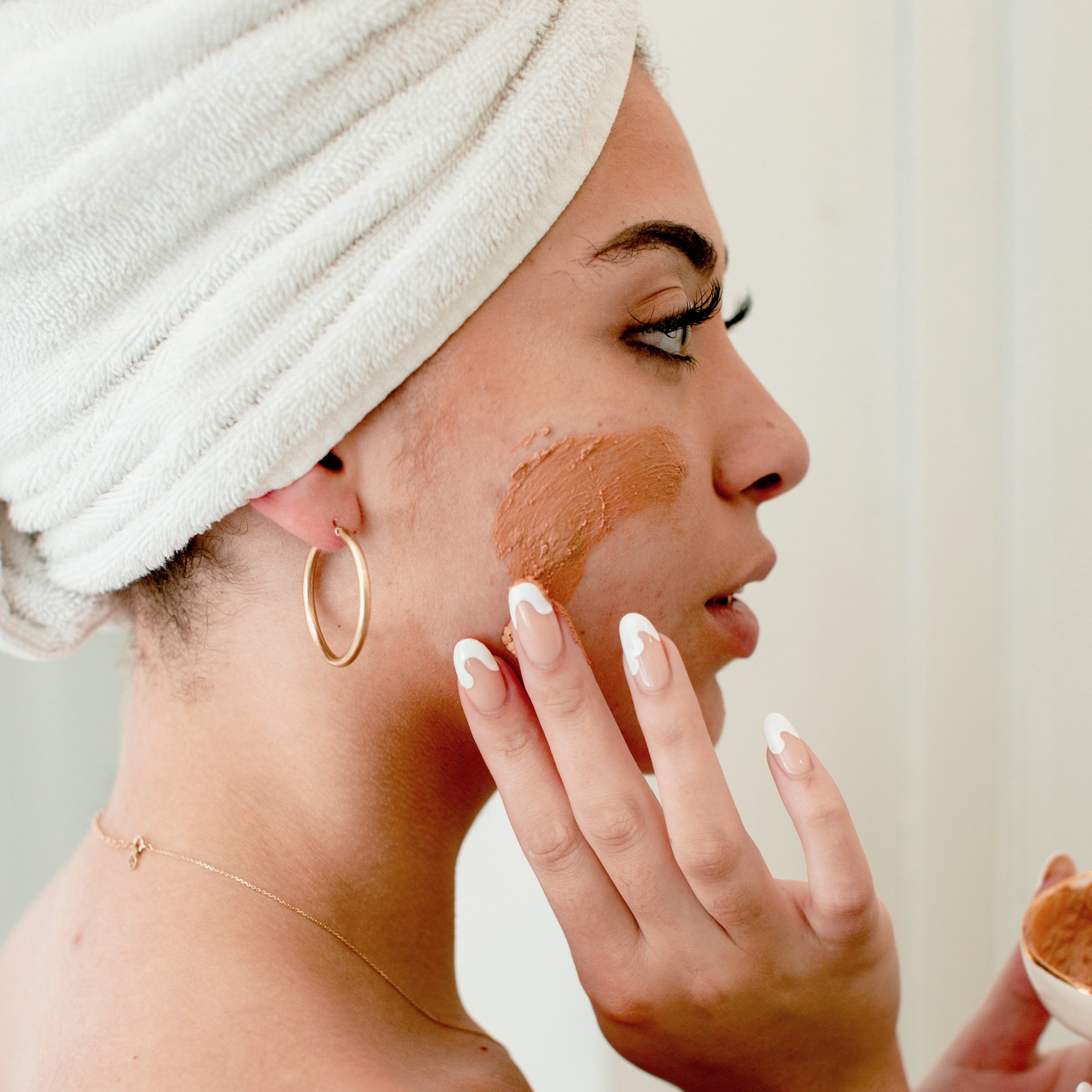 woman-applies-detox-clay-face-mask-to-her-cheeks