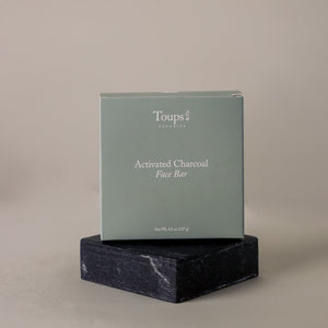 Toups and Co Organics Non Toxic Starter Set in a green box is displayed on a dark, rectangular stone against a neutral background.