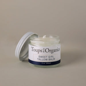 Open jar of Toups and Co Organics Tallow Balm - Sweet Girl, 2 oz (60 ml), with a white lid resting beside it on a neutral background—ideal for providing natural skin nourishment and deep hydration.
