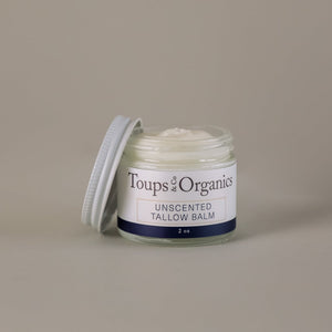 A small glass jar labeled Toups and Co Organics Non Toxic Starter Set with a white screw-on lid resting to the side, filled with a creamy balm.