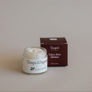 An open jar of Toups and Co Organics Mistletoe Balm sits before its closed maroon box on a neutral background, making it an ideal Christmas gift.