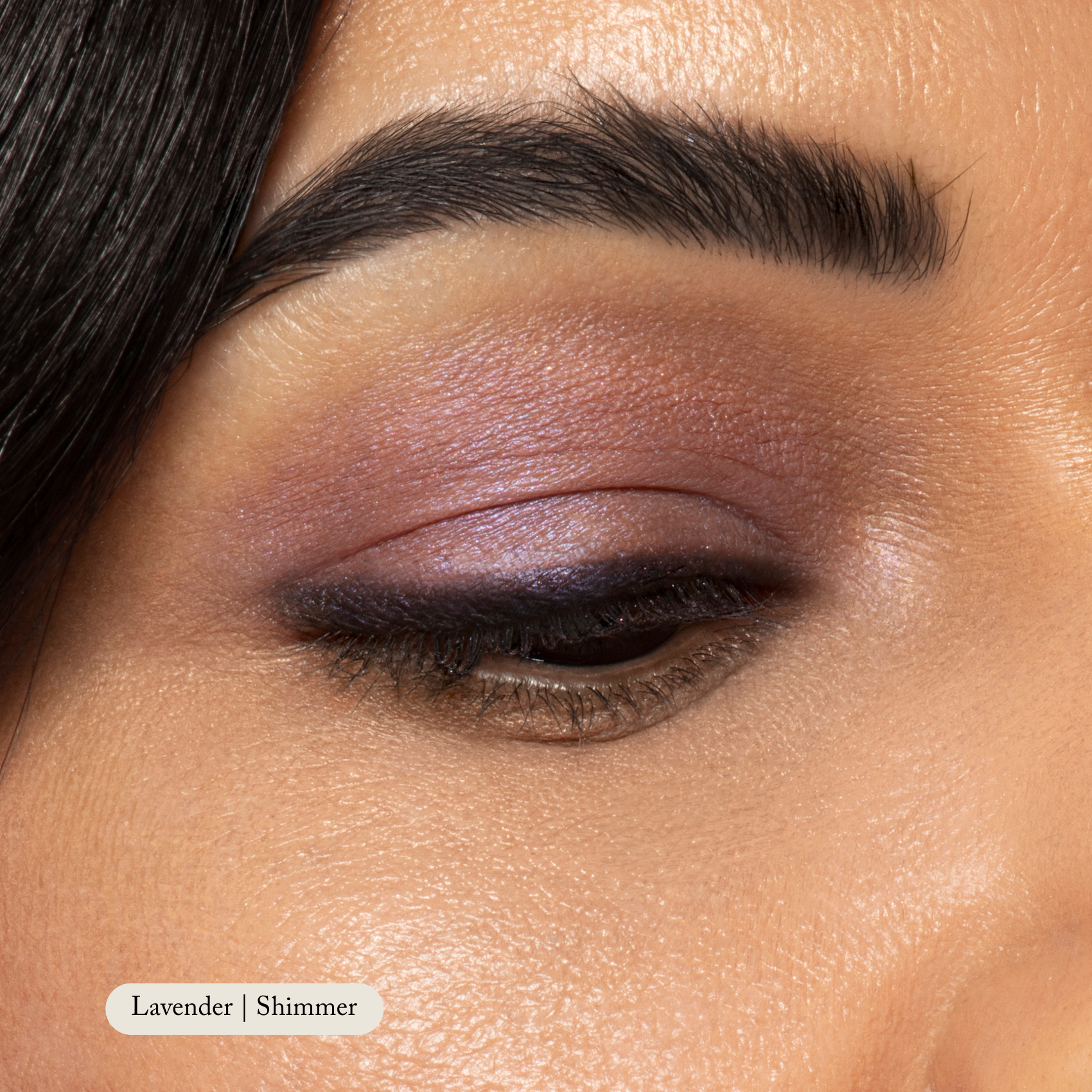 Close-up of a closed eye featuring Toups and Co Organics Natural Eyeshadow Singles in a highly pigmented lavender shimmer, paired with a well-groomed eyebrow above.