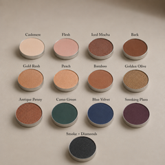 Twelve round, richly pigmented Toups and Co Organics Natural Eyeshadow Singles, each labeled with names in various shades, are arranged in rows on a tan background. This magnetic eyeshadow palette allows you to customize your look with clean, single pans for effortless, vibrant color every time.