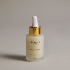 A glass dropper bottle labeled Toups and Co Organics Reparative Serum with a gold cap stands on a neutral background—the ideal anti-aging serum for preventing wrinkles.