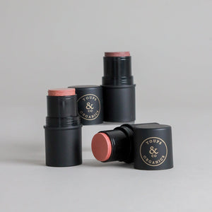 Four Toups & Co non-toxic cheek tints displayed against a clean grey seamless background. The minimalist product image highlights versatile cream makeup designed for an effortless, natural makeup look.