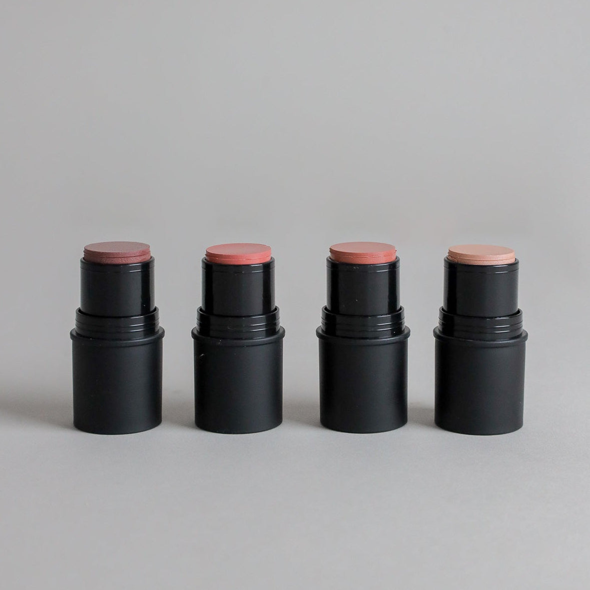 Four Toups & Co cheek tints displayed in a range of flattering shades against a clean grey seamless background. The minimalist product image highlights versatile cream makeup designed for an effortless, natural makeup look.