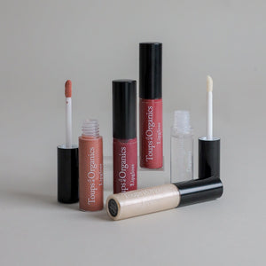 Toups & Co non-toxic lip gloss tubes in clear, shimmer, and rose shades, caps off