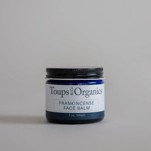 A blue jar of Toups and Co Organics Frankincense Face Balm, a nourishing tallow moisturizer for reducing redness, 2 oz. (60 ml), is shown against a plain light gray background.