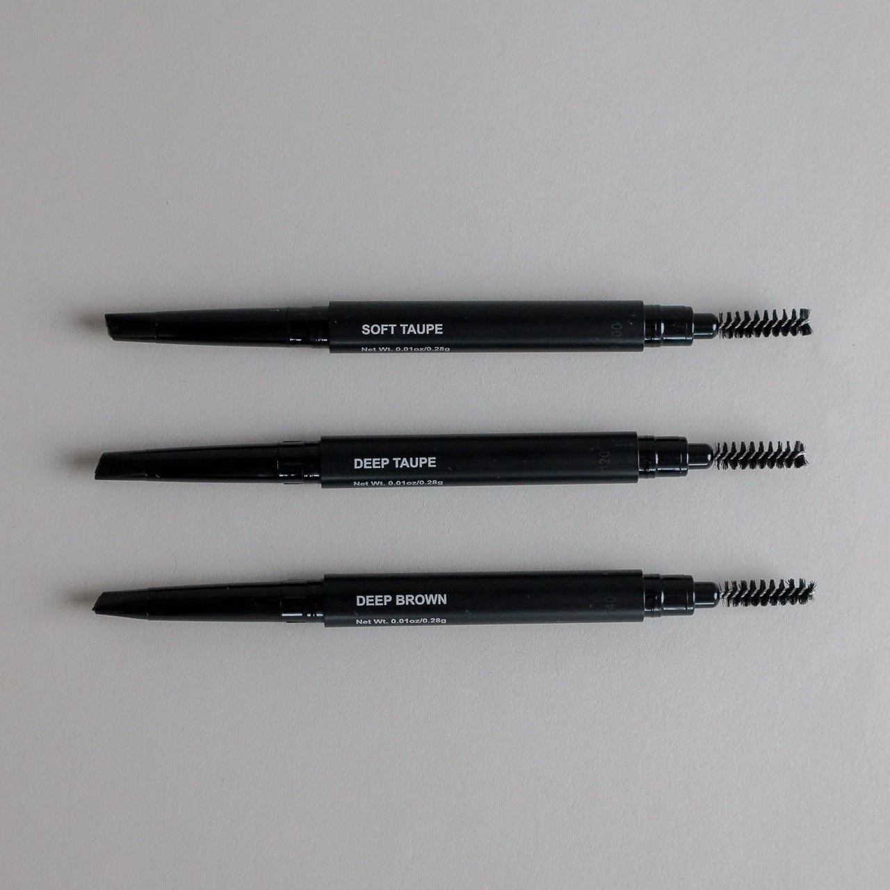 Toups & Co non-toxic brow pencils in Soft Taupe, Deep Taupe, and Deep Brown with spoolie brush