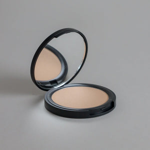 Open compact of non-toxic pressed highlighter powder with mirror