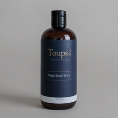 A brown plastic bottle labeled Toups and Co Organics Men’s Body Wash, 12 fl oz, with a black cap, is set against a plain light gray background, showcasing this sulfate-free body wash formulated for men.