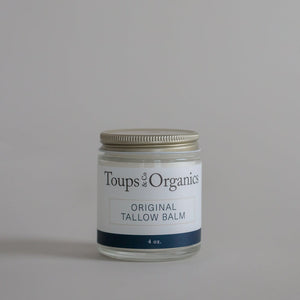 A glass jar of Toups and Co Organics Tallow Balm – Original with a metal lid, expertly formulated for nourishing whole-body moisture and ideal for dry, sensitive skin, displayed on a simple light grey background.