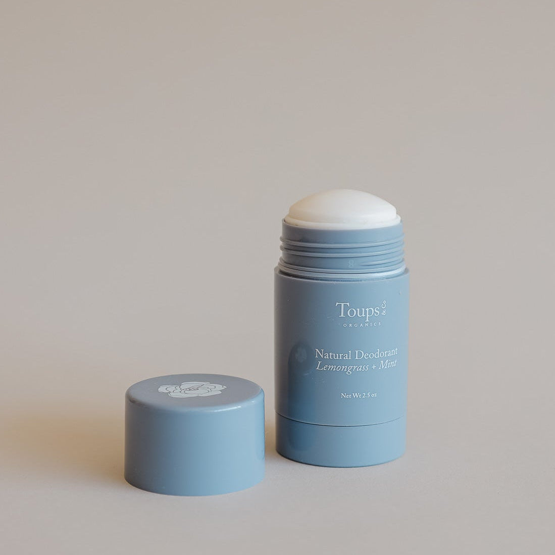 A blue stick of Toups and Co Organics Natural Deodorant with its cap beside it on a neutral background, ideal for those seeking a natural deodorant suitable for sensitive skin.