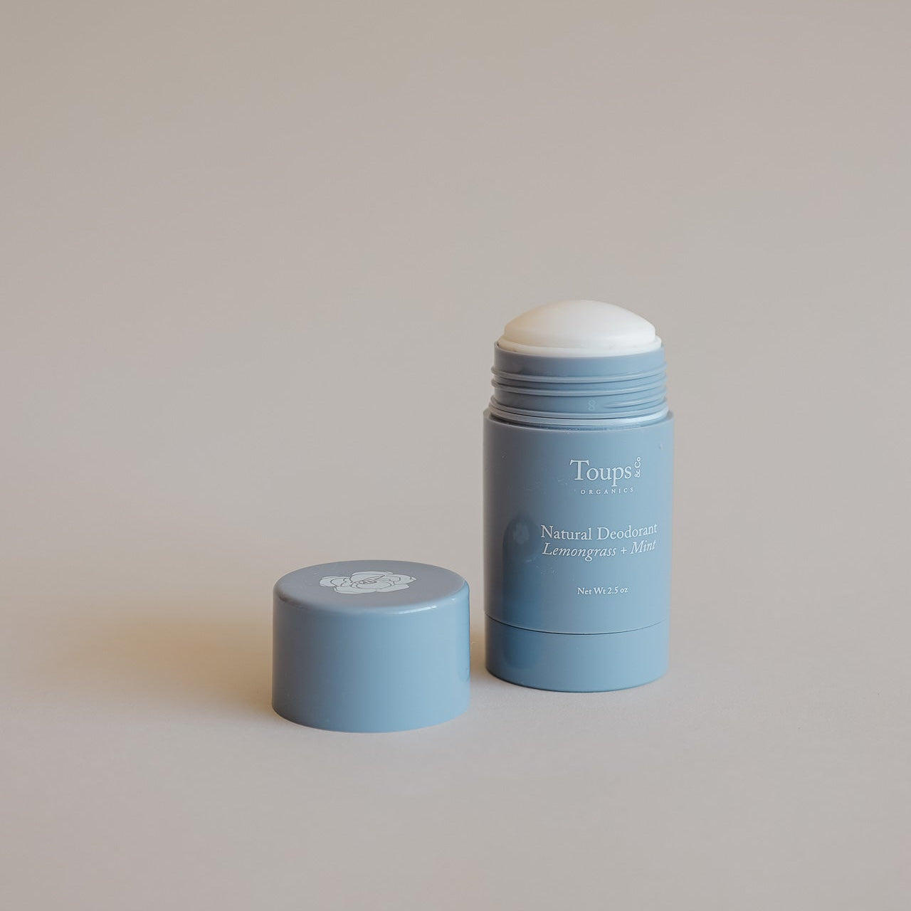 A blue stick of Toups and Co Organics Natural Deodorant with its cap beside it on a neutral background, ideal for those seeking a natural deodorant suitable for sensitive skin.
